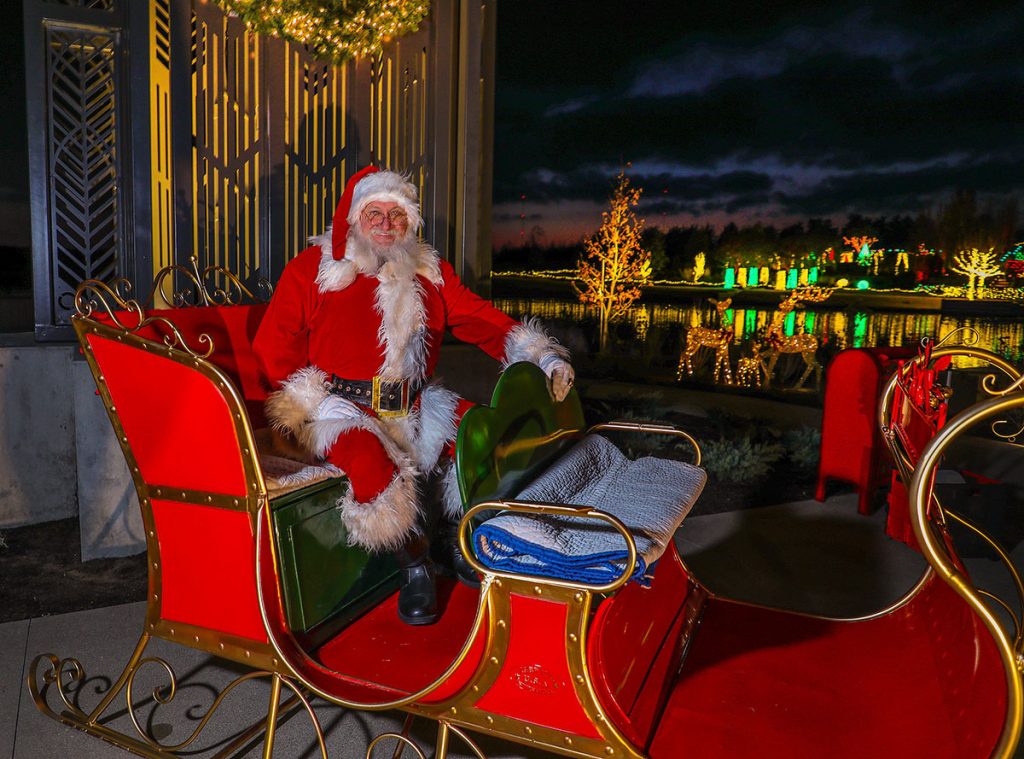 Santa in Sleigh with holiday lights in background